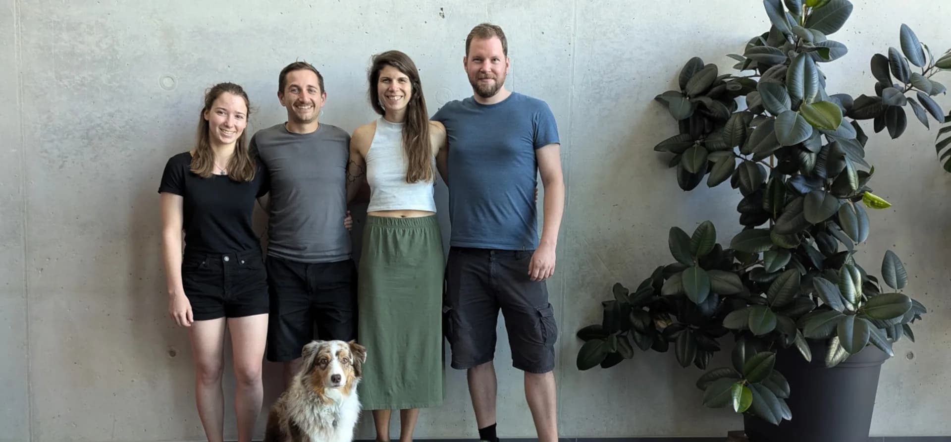Das sixcorners-Gründerteam im Büro vor einer Betonwand, mit Hund